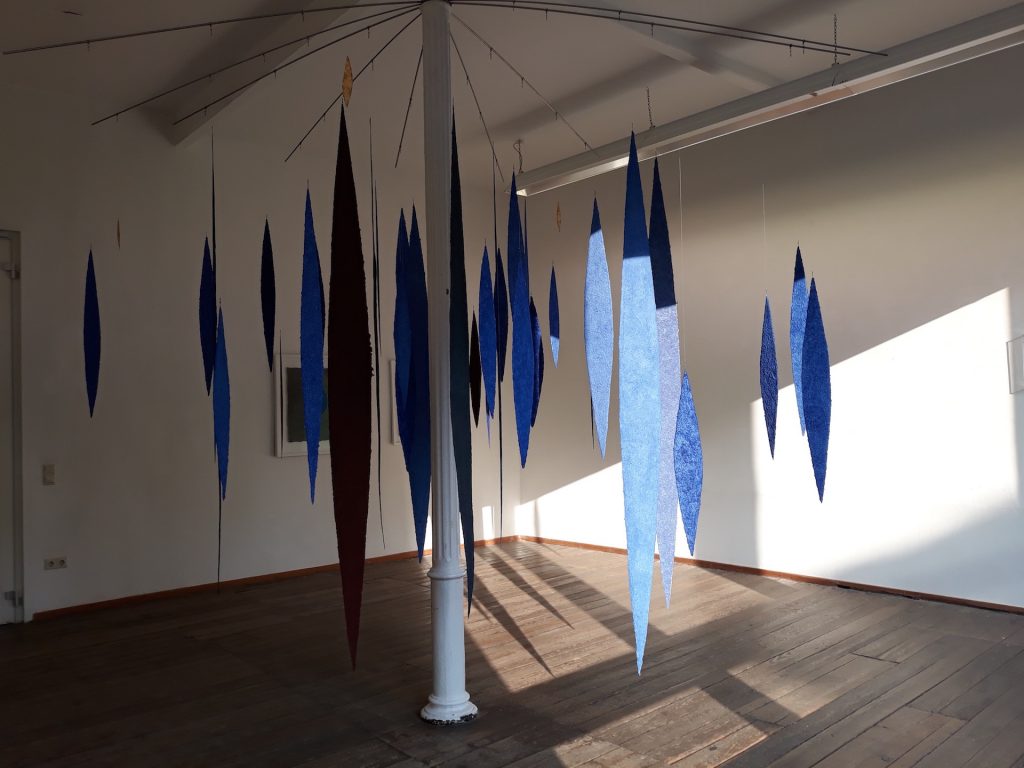 An der Ausstellung papier = kunst 9 im NKV Aschaffenburg im KunstLANDing nimmt Helmut Dirnaichner mit einer Raumarbeit aus 48 geschöpften, schwebenden Lanzettformen aus Lapislazuli und Zinnober teil.